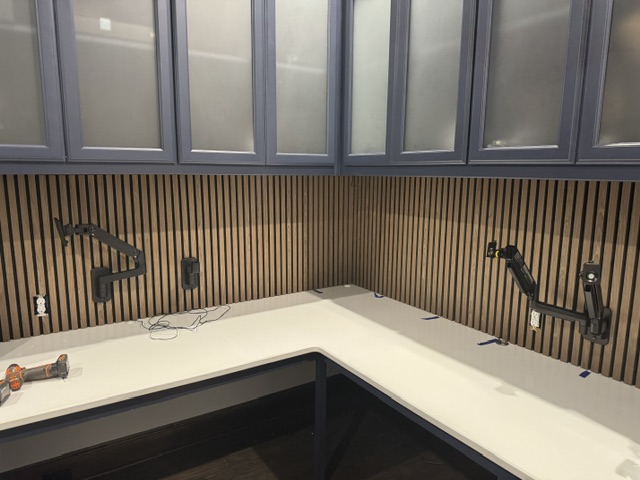 Finished wood slat backsplash with mounted monitor arms